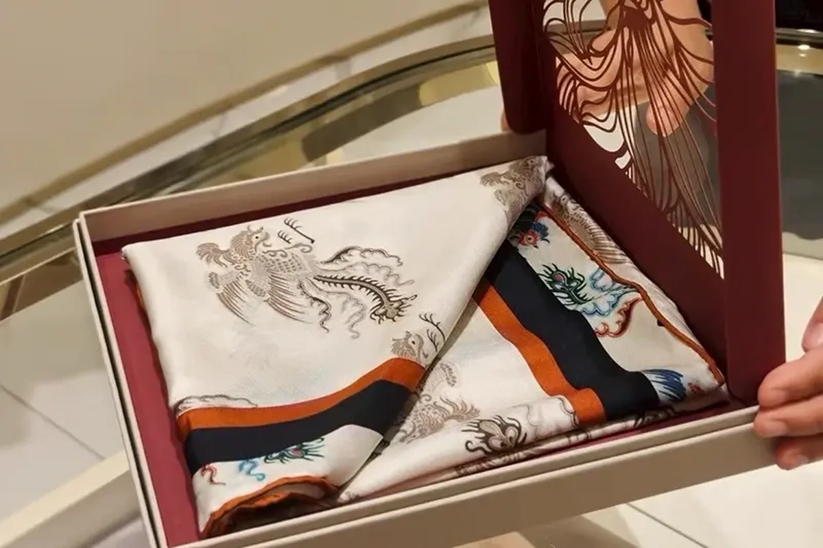 Cream printed scarf with orange and navy borders in an open gift box