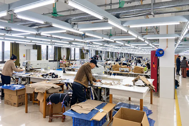Workers preparing garment panels at large cutting and work tables