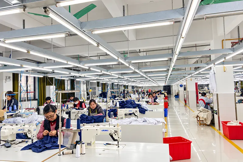 Garment workers operating industrial sewing machines in a shared workshop