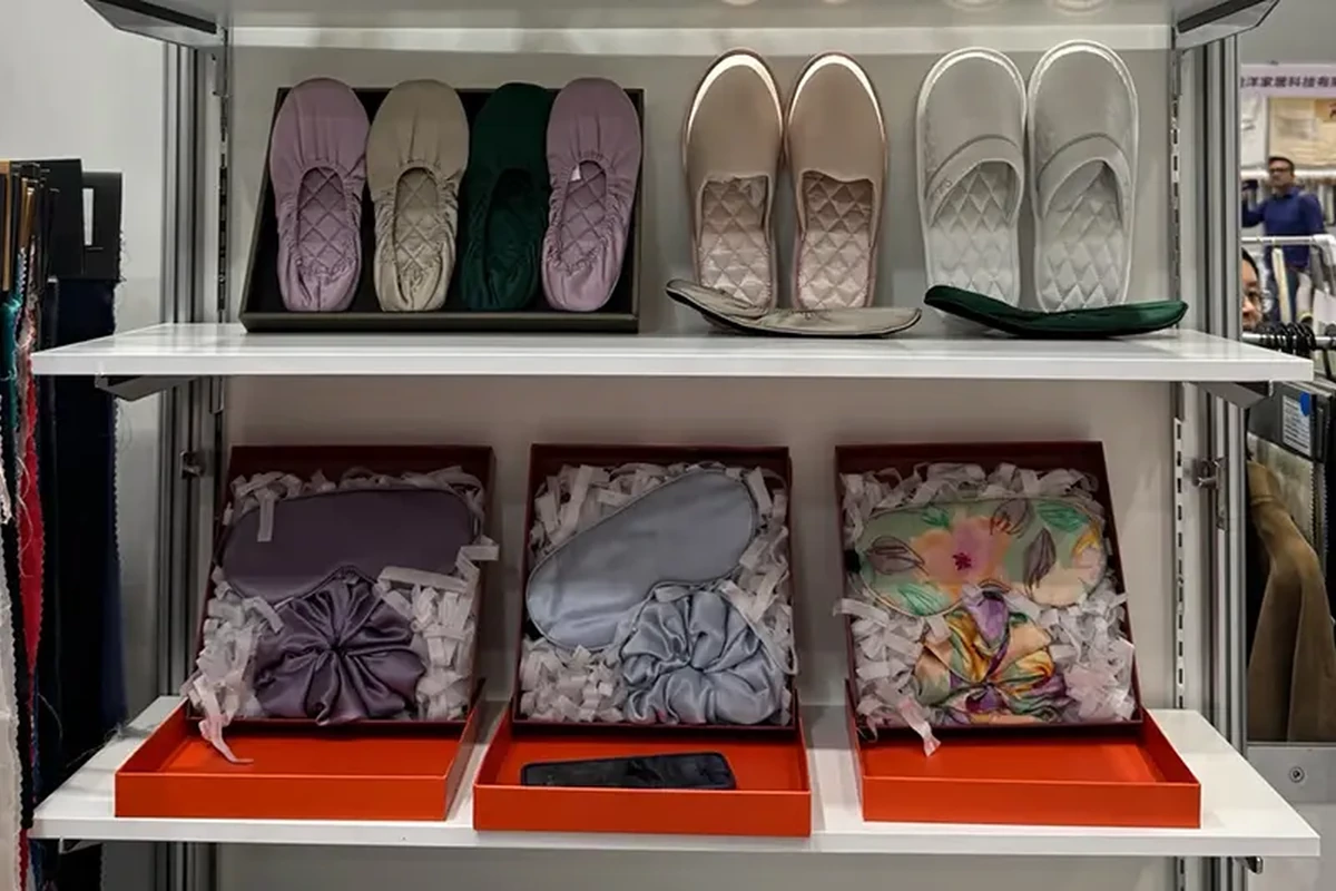 Slippers on an upper shelf and printed scarves in gift boxes below
