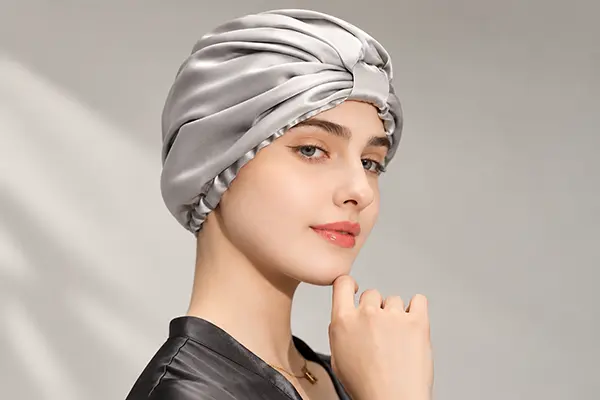 Gray silk bonnet with a broad folded band and gathered crown shown on a model