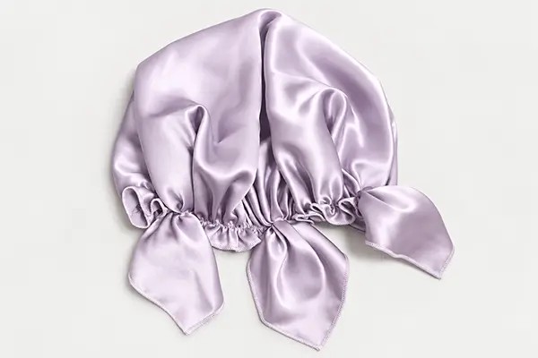 Lilac sleep silk bonnet laid flat with a gathered opening and bow ties