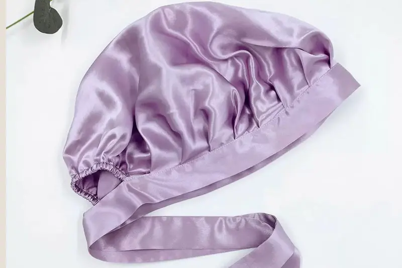 Lilac silk bonnet laid flat with a gathered edge and long matching band