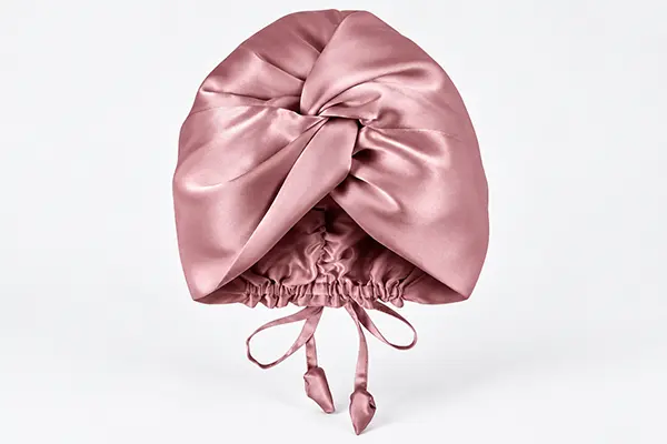 Pink silk bonnet with a large front knot, gathered opening and adjustment ties