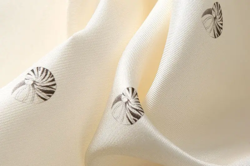 Ivory fabric in soft folds with small dark printed motifs