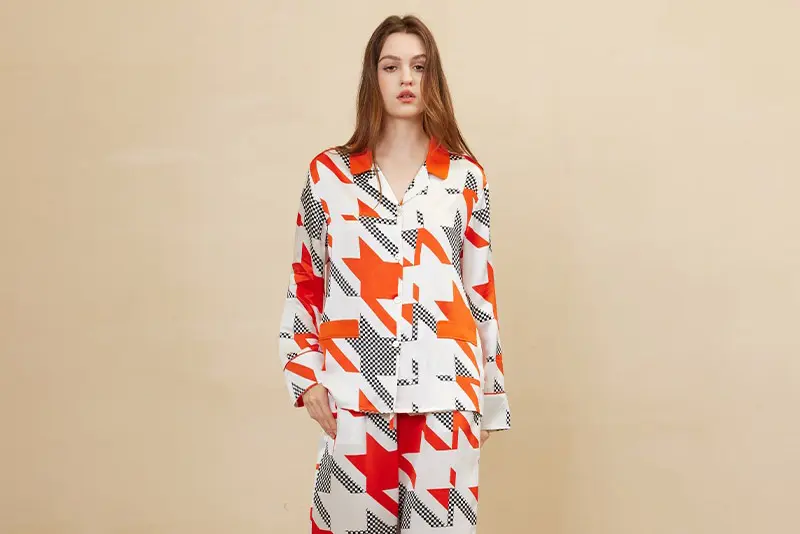 Model wearing silk pajamas with a red, orange, black and white geometric pattern