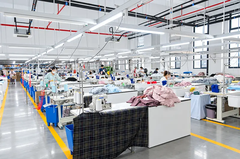 Rows of garment sewing stations and fabric bins on a bright production floor