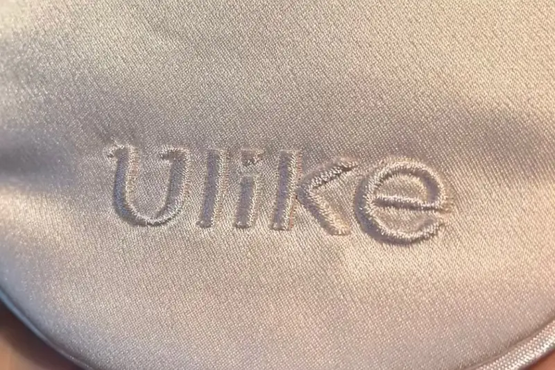 Tone-on-tone embroidered lettering on pale fabric, shown in close-up