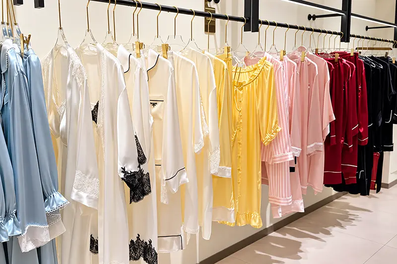 Sleepwear in blue, ivory, yellow, pink, burgundy and black hanging on a rack