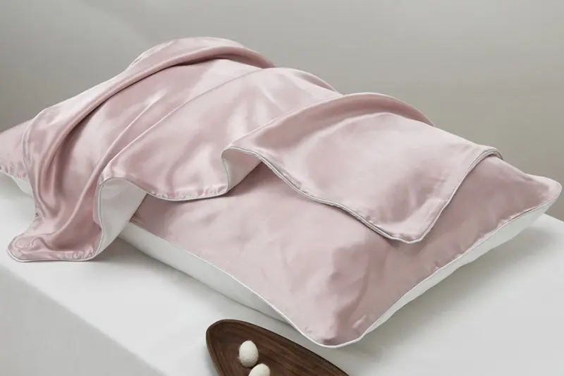 Pale pink silk pillowcase with a wide Oxford border and matching folded fabric