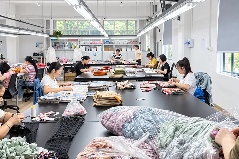 Workers checking and arranging garments across textile finishing tables