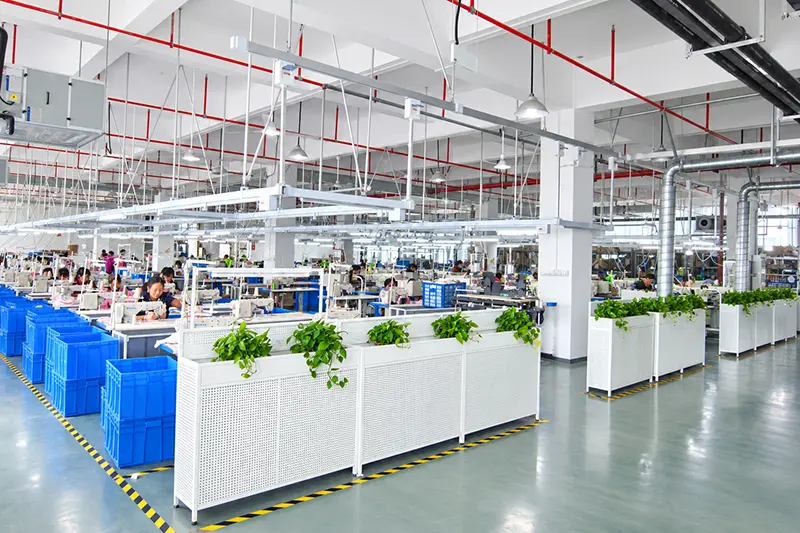 Rows of sewing machines and fabric bins in a garment production workshop