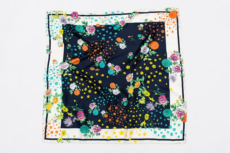 Square silk scarf laid flat with a dark floral center and pale patterned border
