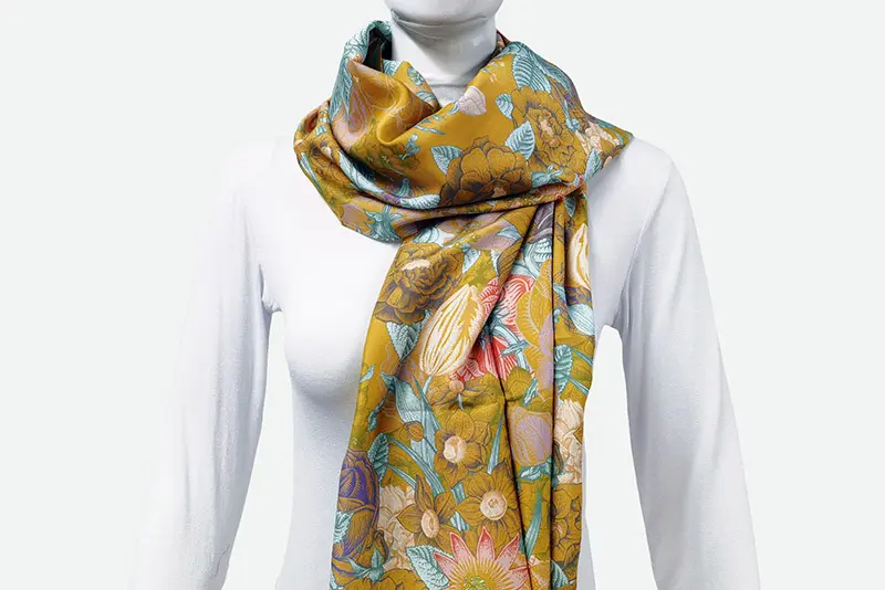 Long gold-toned floral silk scarf draped around a mannequin's neck