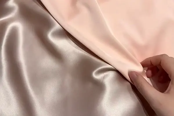Pale pink and silver fabric held together to show contrasting folds and sheen