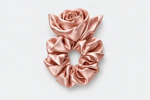 Rose pink silk scrunchie with a sculpted fabric rose and leaf-shaped details