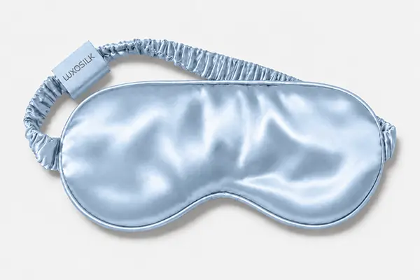 Pale blue silk sleep mask with a curved lower edge and gathered elastic strap
