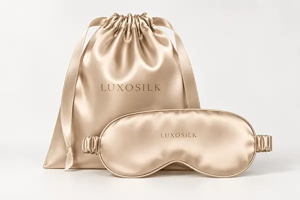 Gold silk sleep mask beside a matching drawstring travel pouch