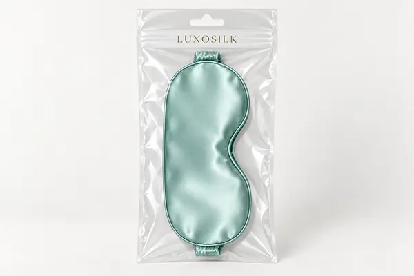 Mint silk sleep mask displayed inside a clear hanging retail bag