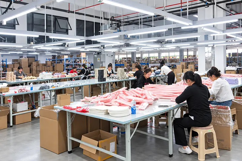 Workers sorting and checking pink textile pieces at workshop tables