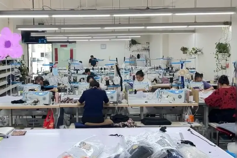 Garment workers sewing at long tables in a production room