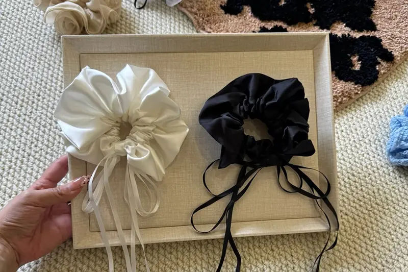 Ivory and black bonnets with long adjustment ties arranged in an open box