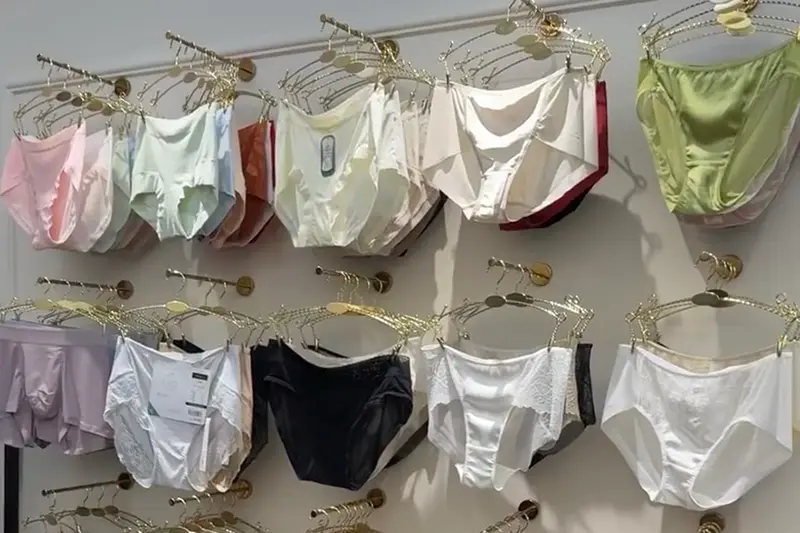 Lingerie and camisole samples in pastel, white and black shades on a showroom wall