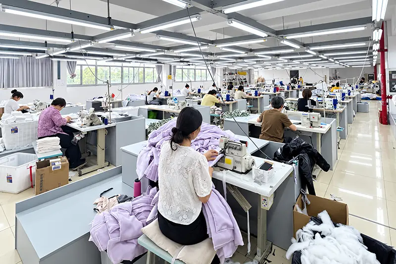 Workers operating sewing machines in parallel rows of garment production stations